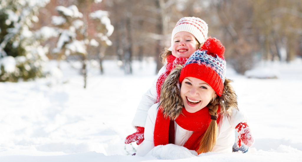 Close-up of a mother while a child on her back laying in the snow