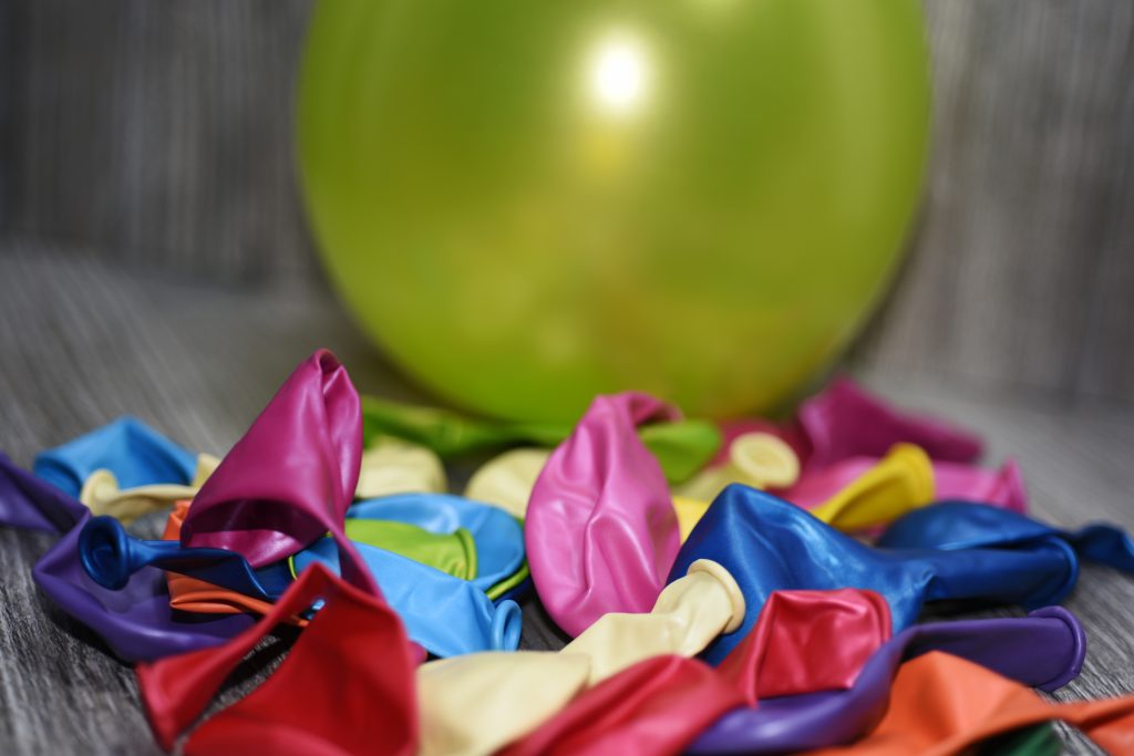  Nahaufnahme von farbigen, entleerten Ballons auf einem Holztisch