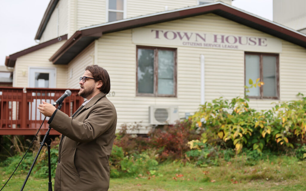 Photo of Will Roy, Community Development Co-ordinator, Cape Breton Regional Municipality Planning, speaking in front of a house with a sign that says "Town House, Citizens Service League"