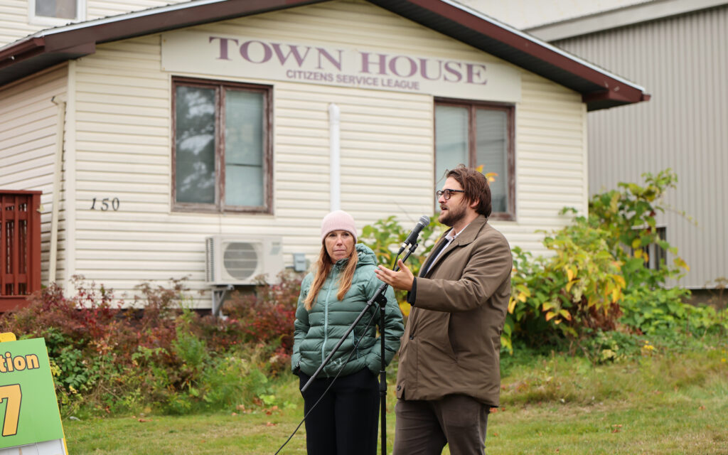 Photo of Will Roy, Community Development Co-ordinator, Cape Breton Regional Municipality Planning, speaking in front of a house with a sign that says "Town House, Citizens Service League"