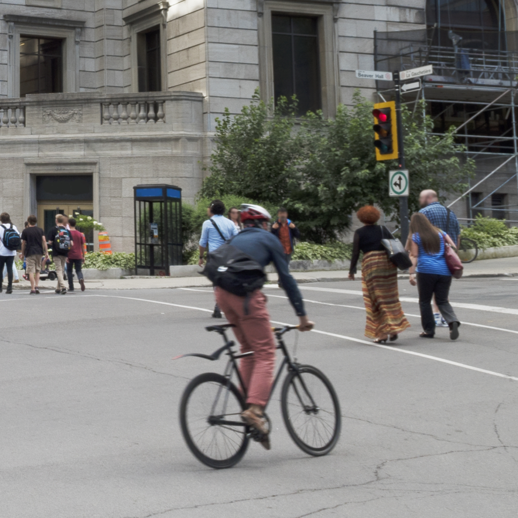 Photo of bicyclist and pedestrians on a busy street.